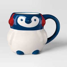 a blue and white penguin mug with red ears