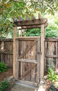 an open wooden gate in the middle of a garden