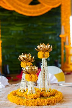 yellow flowers are placed in the center of a table with white and gold decorations on it