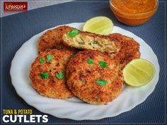 three crab cakes on a white plate next to a bowl of sauce and lemon wedges