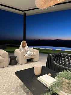 a woman sitting on top of a couch in a living room next to a window