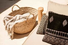 a woven basket sitting on top of a table next to pillows and a wooden stick