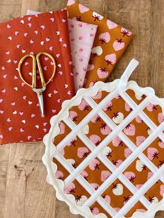 three pieces of fabric sitting on top of a table next to scissors and napkins