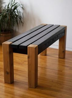 a wooden bench sitting on top of a hard wood floor next to a potted plant