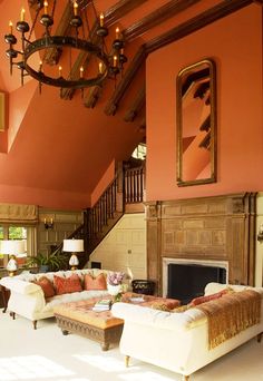 a living room with orange walls and white furniture in the center is an ornate chandelier