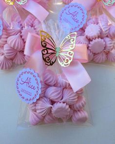 pink and gold butterfly shaped cookies in cellophane bags with name tags on them