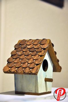 a wooden birdhouse with lots of pennies on the roof