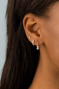 a close up of a woman's ear with two small diamond earrings on it