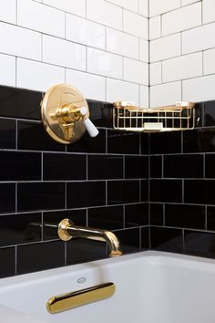 a black and white tiled bathroom with gold faucet, soap dispenser and bathtub