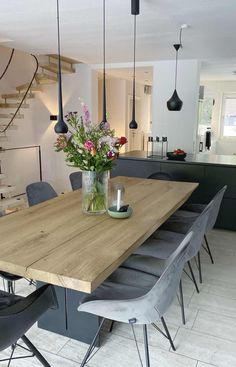 a wooden table surrounded by grey chairs in a room with white walls and flooring