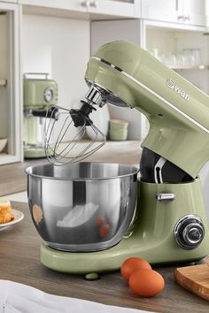 a green mixer sitting on top of a kitchen counter next to an orange and white plate