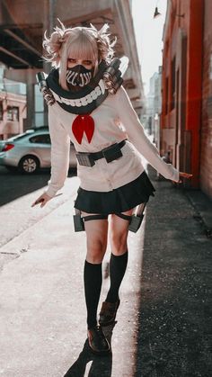 a woman dressed up as a clown walking down the street with her hands in her pockets