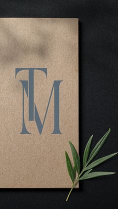 a close up of a paper with the letter t on it and a plant next to it