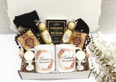 two coffee mugs are sitting in a gift box with chocolates and candies