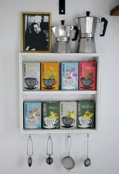 a shelf with coffee cups and spoons hanging on it's sides next to a framed photograph