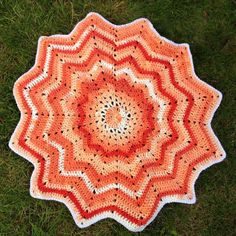 an orange and white crocheted doily on grass