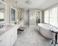 a large bathroom with white fixtures and marble counter tops, along with a claw foot tub