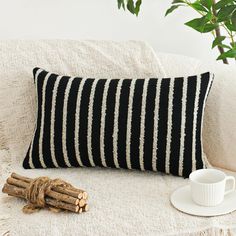 a black and white striped pillow sitting on top of a couch next to a cup