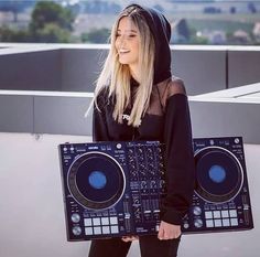 a woman is holding a dj's controller in front of her face and wearing a hoodie