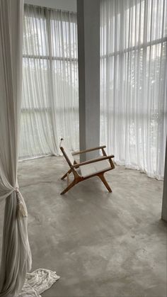 a chair sitting in the middle of a room with sheer curtains on the walls and floor