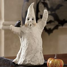 a statue of a ghost with a bird on it's hand next to a pumpkin