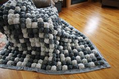 a pile of balls on top of a rug in a living room with hardwood floors