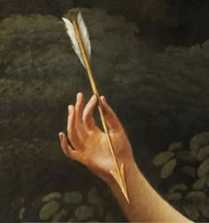 a hand holding a feather on top of rocks