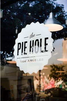 the pie hole sign is hanging in front of the store's glass door window