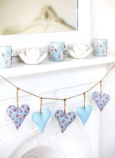 teacups and cups are hung on a string near a fireplace mantel with floral decorations