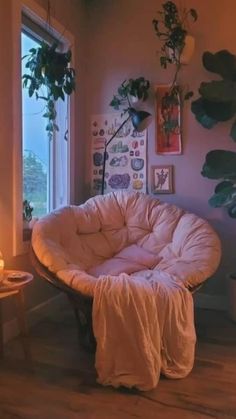 a living room filled with lots of plants next to a window and a chair on the floor