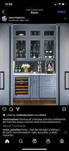 an instagramted photo of a kitchen with blue cabinets and wine bottles on the shelves