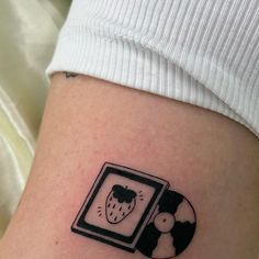 a small tattoo on the side of a woman's leg that has an image of a strawberry in a frame