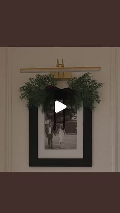 a black and white photo hanging on a wall next to a frame with a wreath