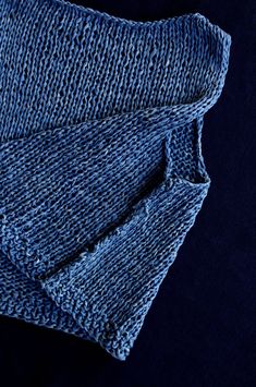 a blue knitted cloth folded on top of a black surface with the fabric pulled back