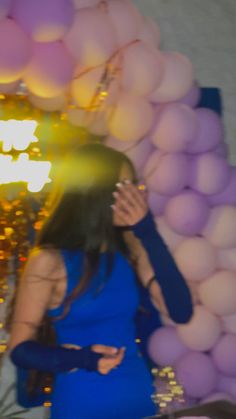 a woman in a blue dress standing next to balloons