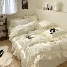 an unmade bed in a bedroom with white sheets and pillows on top of it