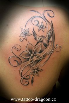 the back of a woman's shoulder with a bird and flower tattoo on it