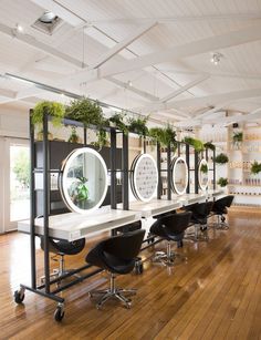 an empty room with several chairs and mirrors on the wall, along with potted plants