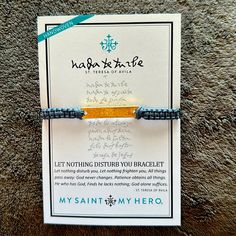 a bracelet with an orange and blue bead is on display in front of a card that says, let nothing disturb you braceletlet