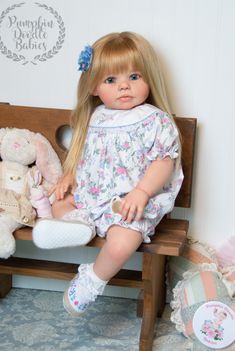 a doll sitting on a wooden bench next to a stuffed animal