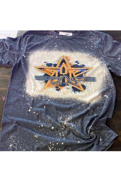 a t - shirt that is on top of a wooden table with paint splattered over it