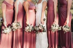 a group of women standing next to each other wearing dresses and holding bouquets in their hands