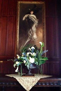 a painting hangs above a table with flowers on it