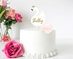 there is a cake with a swan on it and flowers in the vase behind it