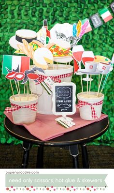 a table topped with lots of cupcakes and cake toppers next to a green wall