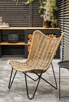 a wicker chair sitting on top of a patio next to a table with plants