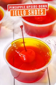 three plastic cups filled with jello shots on top of a white wooden table and the words pineapple upside - down jello shots above them