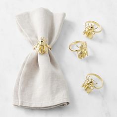 three gold rings sitting on top of a white napkin next to two other pieces of jewelry