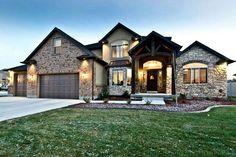 a large house with stone and brick accents in the front yard at dusk, surrounded by green grass