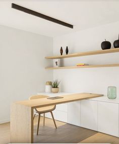 a wooden table sitting on top of a hard wood floor next to white shelves filled with potted plants